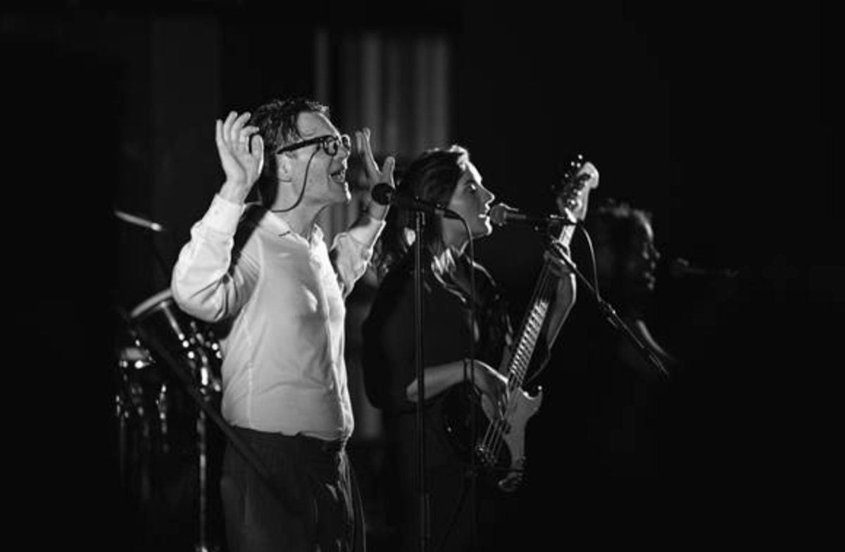 Black and white photo of Talking Heads tribute band Start Making Sense performing live with vocalist gesturing and bass player singing.